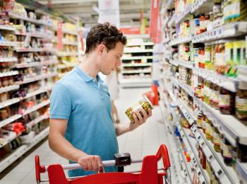 Een jongeman doet boodschappen in de supermarkt.